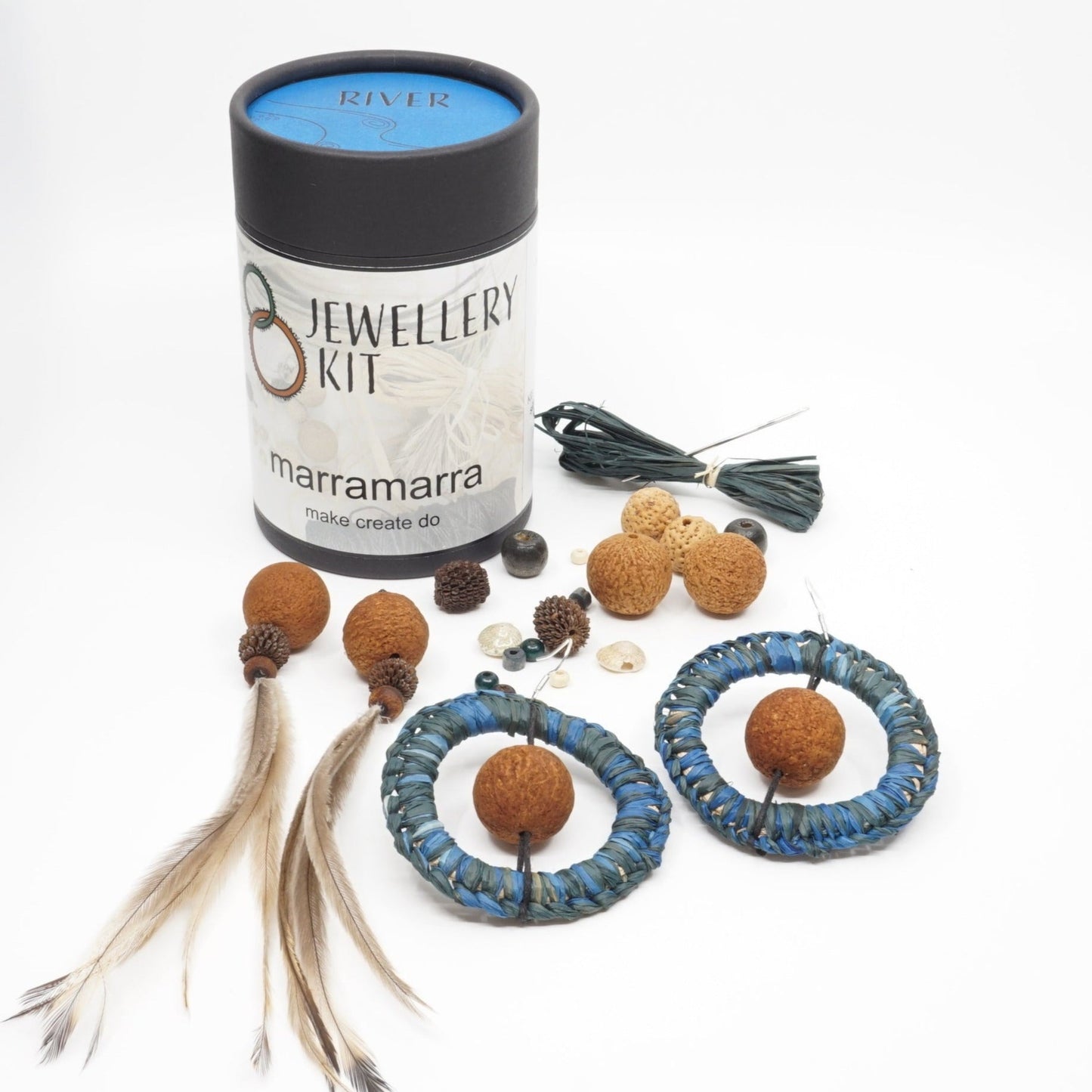River teal earrings made from raffia, seeds, feathers and beads spread out of an Aboriginal jewellery kit